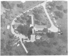 View of the seminary from above, with many cars parked and people gathered before a tent