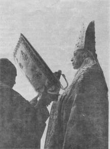 Pope Pius XII reads from a large book in the canonization of St. Pius X