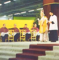 Archbishop Lefebvre gives the homily, beside the MC, with four bishops seated at the side